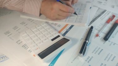 Bazı hesaplamalar yapan ve mali rapora not alan bir erkeğin yakın çekim çekimi.