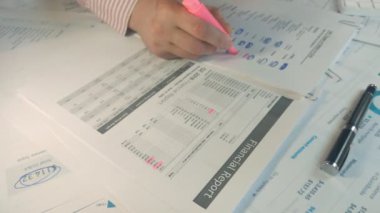 Finansal raporda işaretli rakamların altını çizen ellerin yakın plan görüntüsü