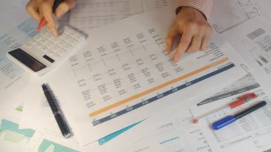 Muhasebecinin eli hesap makinesinin yakın plan mali raporlarını sayıyor.