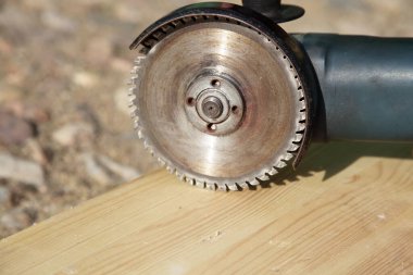 Dairesel testereli kullanışlı bir öğütücü ahşap bir tahtayı yakın çekimde testereyle kesiyor - DIY elle kumanda aletleri