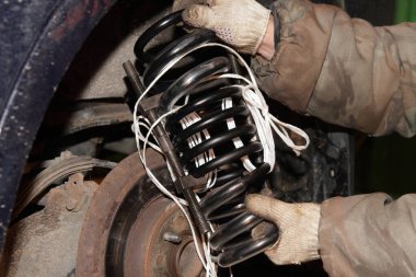 Şişe hidrolik arka planındaki kırık arabada yeni bobin yayı. Garajda araç süspansiyonu tamiri.