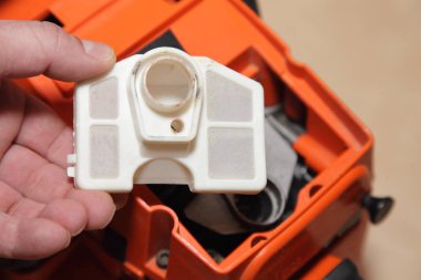 Bir adamın beyaz eli testereyi temiz hava filtresinden tutarken yakın çekim sonrası elektrikli teçhizat servisini kullandıktan sonra