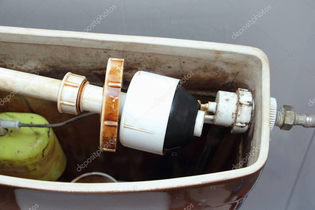 Old sanitary equipment valves  in the dirty drain water tank close up - DIY lavatory repair at home