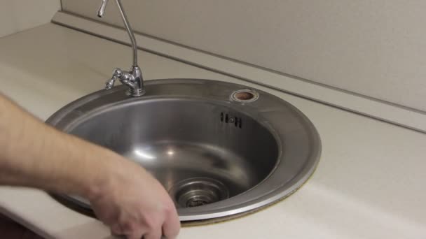 用水暖工白手从厨房的白色桌子上拆卸旧的灰色不锈钢水槽 — 图库视频影像