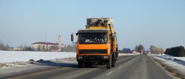 Sarı kamyonet Avrupa 'nın boş kırsal kesiminde kış yolunda. Ön manzara. Ulaşım lojistiği.