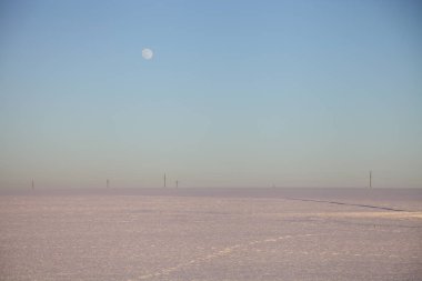 Kış günü mavi gökyüzünde dolunaylı, sonsuz kar tarlası. Avrupa doğal manzarası.