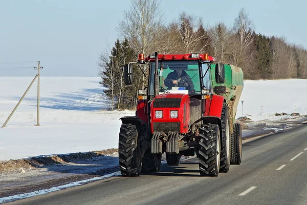 ロシアの舗装された冬の田舎道上の重い大きな赤い車輪付きトラクター 正面図 ヨーロッパの農村輸送物流 — ストック写真