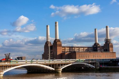 Londra 'daki Battersea Elektrik İstasyonu. 1935' te Thames Nehri üzerinde inşa edilmiş kömür ateşli bir bina. Oradan geçen tren, toplu taşıma altyapısını, stok fotoğrafı görüntüsünü gösteriyor.