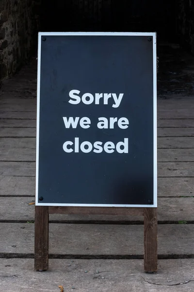 Sorry we are closed information notice board sign on a chalkboard blackboard wooden frame placard with white text on a black background, stock photo image