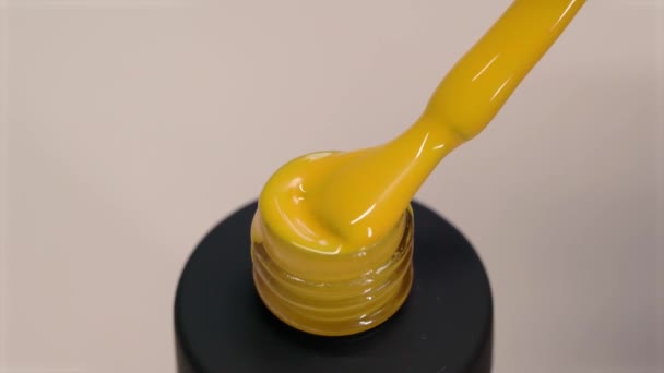 Gel polish yellow thick texture. Varnish flows from a brush into a black tube — Stock Video