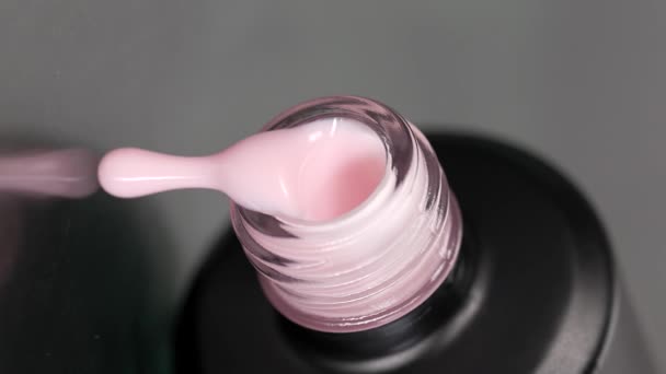 Vidéo verticale. Le vernis gel rose sort lentement de la bouteille sur la table — Video