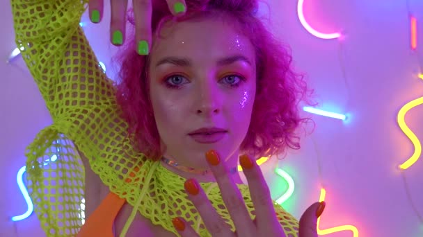 Una donna con i capelli rosa mostra una manicure luminosa sulle unghie. sfondo al neon — Video Stock