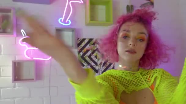 Όμορφη χορεύτρια με ροζ μαλλιά χορεύει σε ένα δωμάτιο με φωτεινό νέον διακόσμηση — Αρχείο Βίντεο