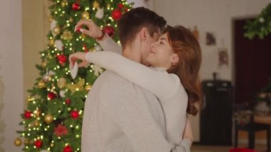 Genç ve mutlu bir çift. Birbirlerine aşık. Noel ağacının yanında sarılıyorlar.