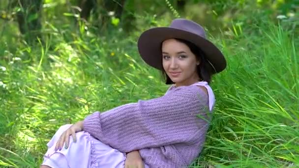 Een gelukkige jonge brunette in een hoed op een zonnige zomerdag toont emoties — Stockvideo