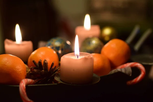 Three burning candles with manadarins and a pine cone as christmas decoration — Stock Photo, Image