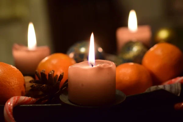 Tres velas encendidas con manadarines y un cono de pino como decoración navideña —  Fotos de Stock