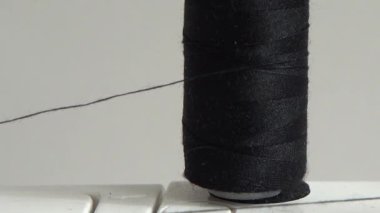Dikiş makinesi bir makaraya iplik takıyor.