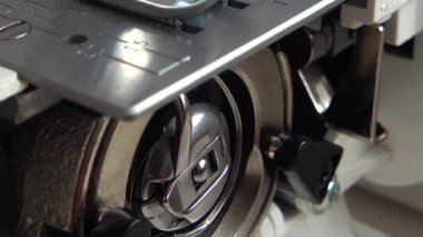 Dikiş makinesinin iğnesi iplik diker. Dikiş makinesi mekanizmasının elementleri iş başında. Bir dikiş makinesinin iç parçaları.