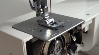 Dikiş makinesinin iğnesi iplik diker. Dikiş makinesi mekanizmasının elementleri iş başında. Bir dikiş makinesinin iç parçaları.