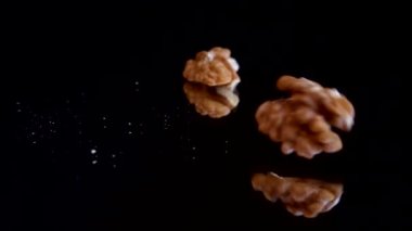 Ceviz çekirdekleri siyah ayna yüzeyine düşer. Ağır çekim. Juglans regia.