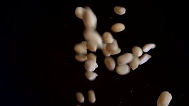 Kaçık. Çiğ yer fıstığı siyah ayna yüzeyine düşer. Yavaş çekim.