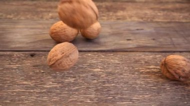 Cevizler eski ahşap bağbozumu tahtasına dökülüyor. Ağır çekim. Juglans regia.