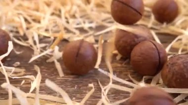 Kabuklu Macadamia fındıkları saman ve eski ahşap vintage tahtanın üzerine düşer. Yavaş çekim.