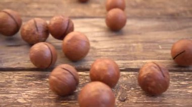 Kabuklu Macadamia fındıkları eski ahşap şarap tahtasına düşer. Yavaş çekim.