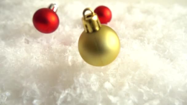 雪の上でクリスマスのおもちゃを落下 装飾的な背景 スローモーション — ストック動画