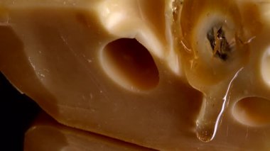 Aynalı siyah arka planda peynirden bal damlaları akıyor..