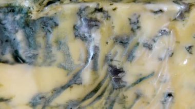 Dorblu peynirinden akmakta olan bal damlaları aynalı siyah arka planda.