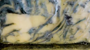 Dorblu peynirinden akmakta olan bal damlaları aynalı siyah arka planda.