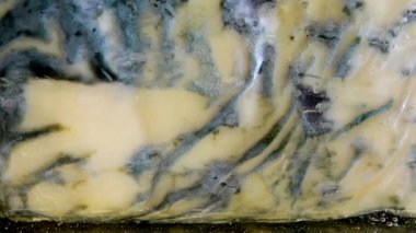 Dorblu peynirinden akmakta olan bal damlaları aynalı siyah arka planda.