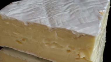 Brie peynirinden damlayan bal damlaları aynalı siyah arka planda.