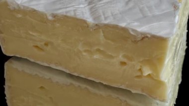 Brie peynirinden damlayan bal damlaları aynalı siyah arka planda.