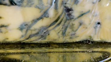 Dorblu peynirinden akmakta olan bal damlaları aynalı siyah arka planda.