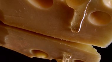 Aynalı siyah arka planda peynirden bal damlaları akıyor..
