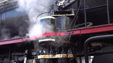 A retro steam locomotive prepares to leave the station.