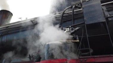 A retro steam locomotive prepares to leave the station.