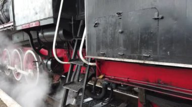A retro steam locomotive prepares to leave the station.
