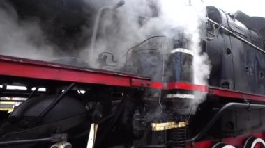 A retro steam locomotive prepares to leave the station.