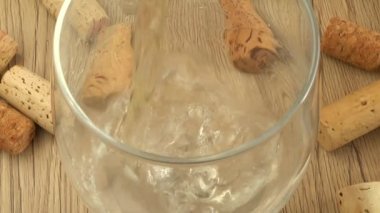 Şarap, şarap mantarlarının arka planındaki bir bardağa dökülür..