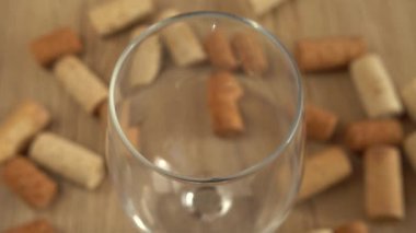 Şarap, şarap mantarlarının arka planındaki bir bardağa dökülür..