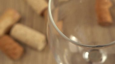 Şarap, şarap mantarlarının arka planındaki bir bardağa dökülür..