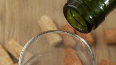 Şarap, şarap mantarlarının arka planındaki bir bardağa dökülür..