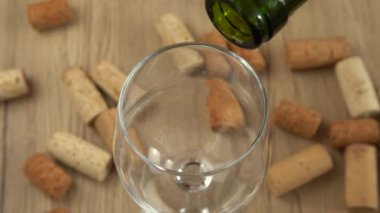 Şarap, şarap mantarlarının arka planındaki bir bardağa dökülür..