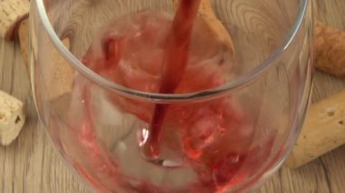 Şarap, şarap mantarlarının arka planındaki bir bardağa dökülür..