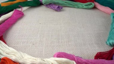 Renkli küf ipliklerinin arka planına karşı çuval bezi üzerine çok renkli makaralar dökülüyor. Yavaş çekim.