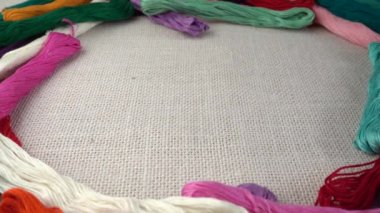 Renkli küf ipliklerinin arka planına karşı çuval bezi üzerine çok renkli makaralar dökülüyor. Yavaş çekim.